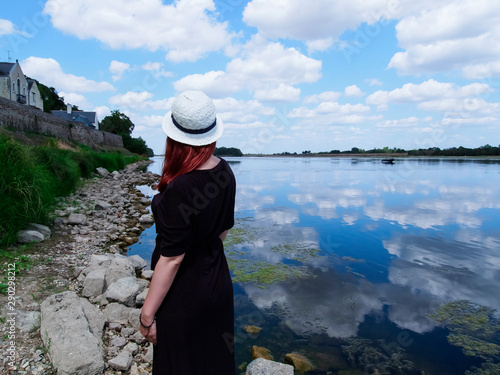 girl in a black and white hat by the river
