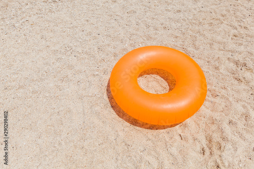 Yellow inflatable ring for swimming at sand beach on summer day