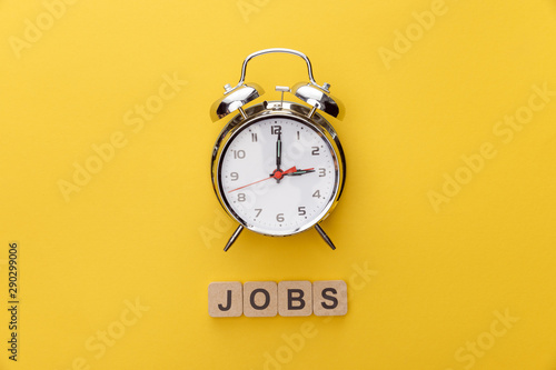 top view of clock and cardboard squares with jobs inscription on yellow background