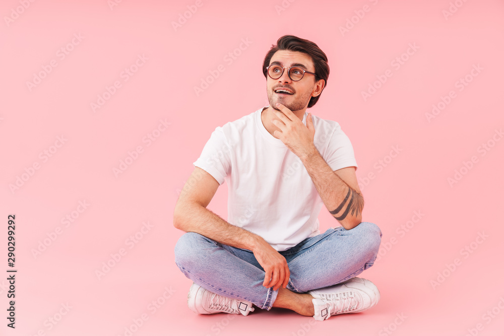 Image of pleased man looking aside while sitting with legs crossed Image of pleased man looking aside while sitting with legs crossed