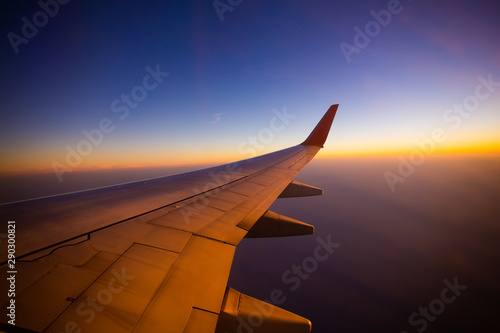 Airplane wing with sunrise in light flare