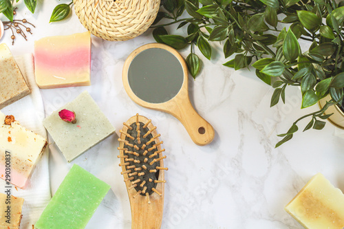 handmade multicolored soap with herbs and rosebuds, comb, towel, mirror, face brush on a marble background with. Spa eco friendly set kit for face and body treatments care flat lay instagram style