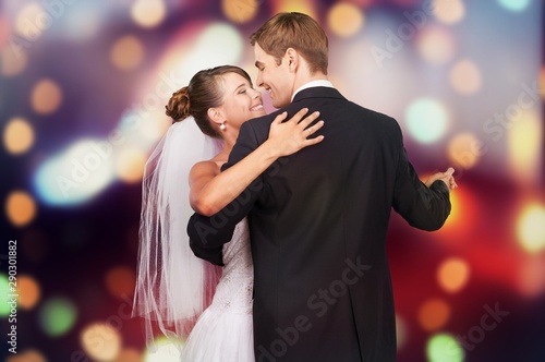 Happy just married young couple dancing on blurred background