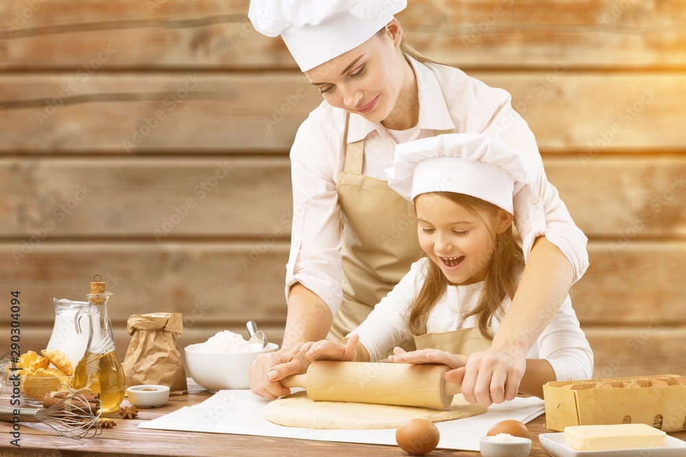 Beautiful young mom and her cute little daughter are playing and smiling while baking in kitchen at home Beautiful young mom and her cute little daughter are playing and smiling while baking in kitchen at home