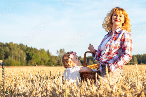 Wallpaper Mural Little girl and girl with curly brown hair holds a wicker basket on a wheat field. Picnic in the countryside, countryside. Torontodigital.ca