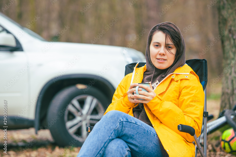 woman sitting in chair outdoors drinking warm up tea car on background  Stock Photo | Adobe Stock
