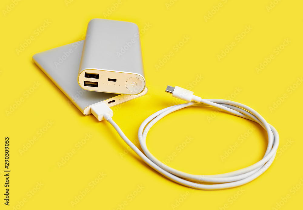 Power bank for charging mobile devices. White smart phone charger with power bank. Battery bank on a yellow background . External battery for mobile devices. Power bank for charging mobile devices. White smart phone charger with power bank. Battery bank on a yellow background . External battery for mobile devices.