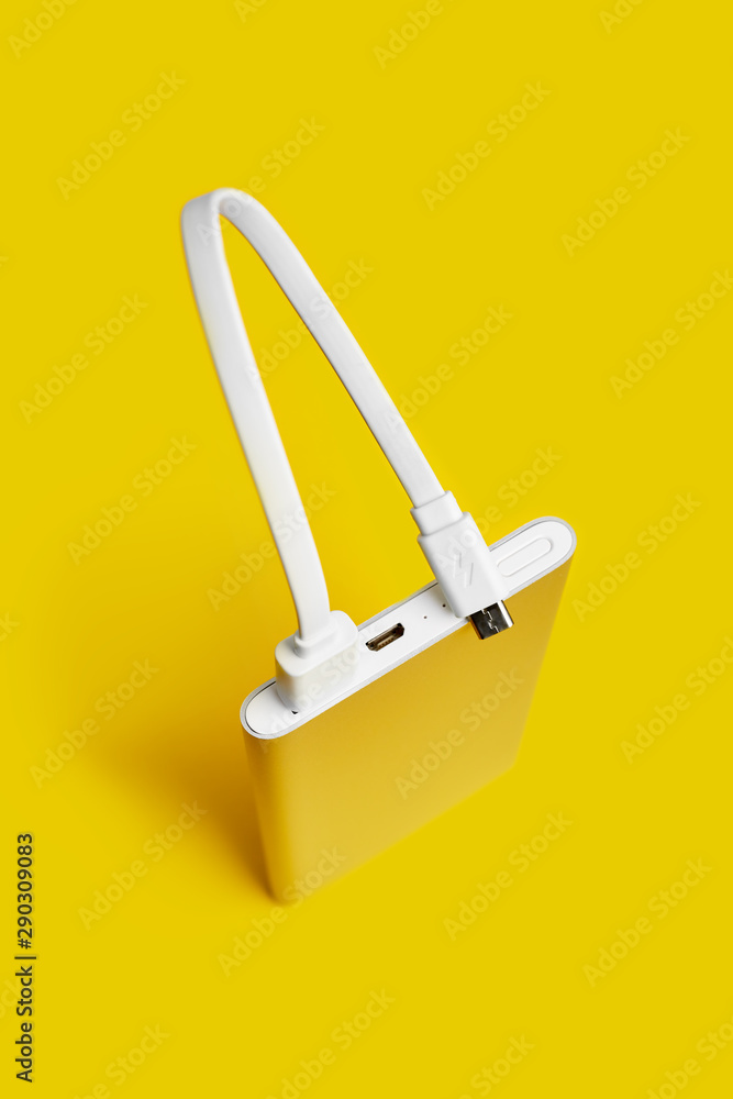 Power bank for charging mobile devices. White smart phone charger with power bank. Battery bank on a yellow background . External battery for mobile devices. Power bank for charging mobile devices. White smart phone charger with power bank. Battery bank on a yellow background . External battery for mobile devices.