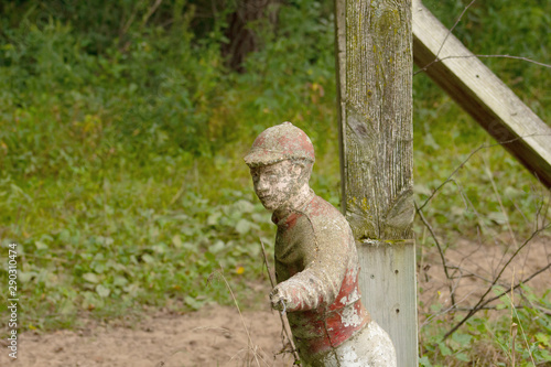 Old broken and weathered statuette of a jockey pointing next to a post