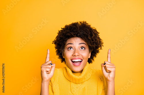 Photo of dark skin pretty lady indicating index fingers up to empty space on cool placard wear warm knitted jumper isolated yellow background