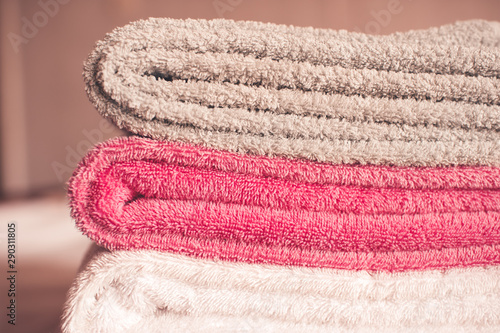 Stack of soft towels staying in bed in hotel room close up. Selective focus.