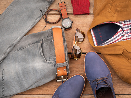 Creative fashion design for men casual clothing set and accessories on wooden background include navy shoes, yellow suit, jeans, belt, sunglass and plaid shirt. Flat lay, top view