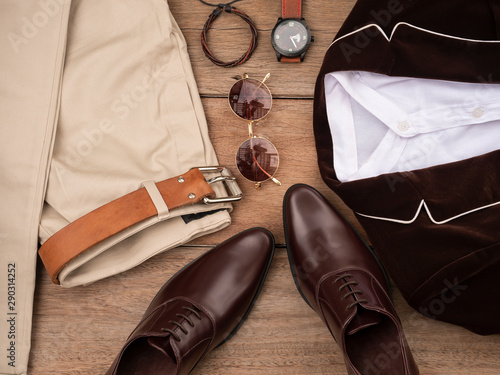 Creative fashion design for men casual clothing set and accessories on wooden background include oxford shoes, brown suit, pants, belt, sunglass, sock and white shirt. Flat lay, top view