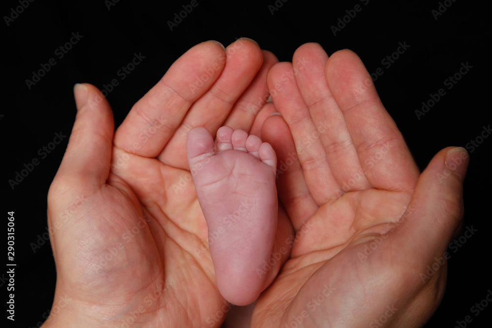 Newborn baby's feet in father's hand