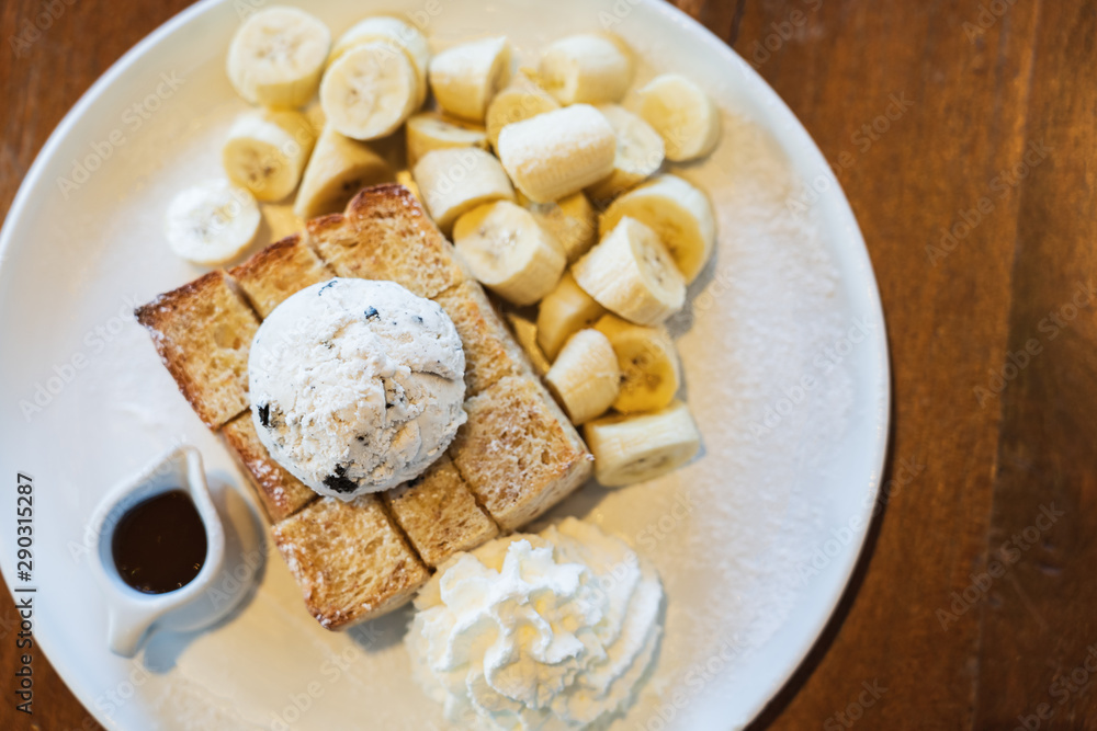 Flat lay on Honey Toast, Bread Buttered Toast, Banana, Ice Cream and Whipped Cream Dessert on a white Dish
