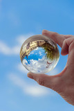 globe in hand, lensball with castle reflection on blue sky