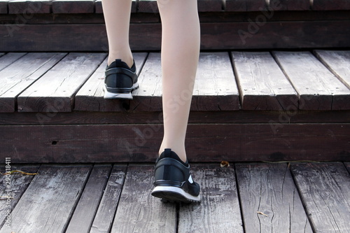 female legs climb the wooden stairs