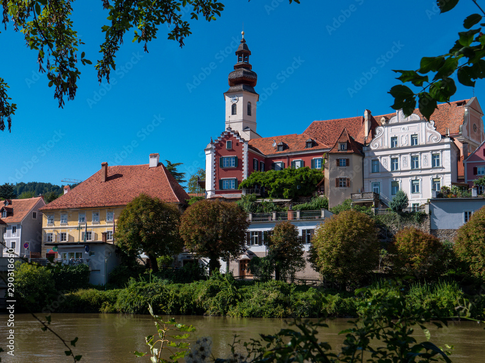 Flusseitige Silouhette von Frohnleiten an der Mur im Bezirk Graz, Österreich mit blauem Himmel, Kirche und historischen Häusern Flusseitige Silouhette von Frohnleiten an der Mur im Bezirk Graz, Österreich mit blauem Himmel, Kirche und historischen Häusern