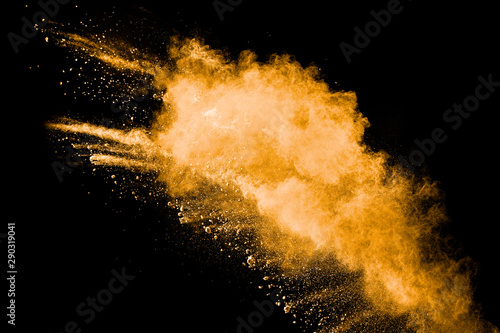 Abstract explosion of orange dust on black background. Freeze motion of orange powder splash.