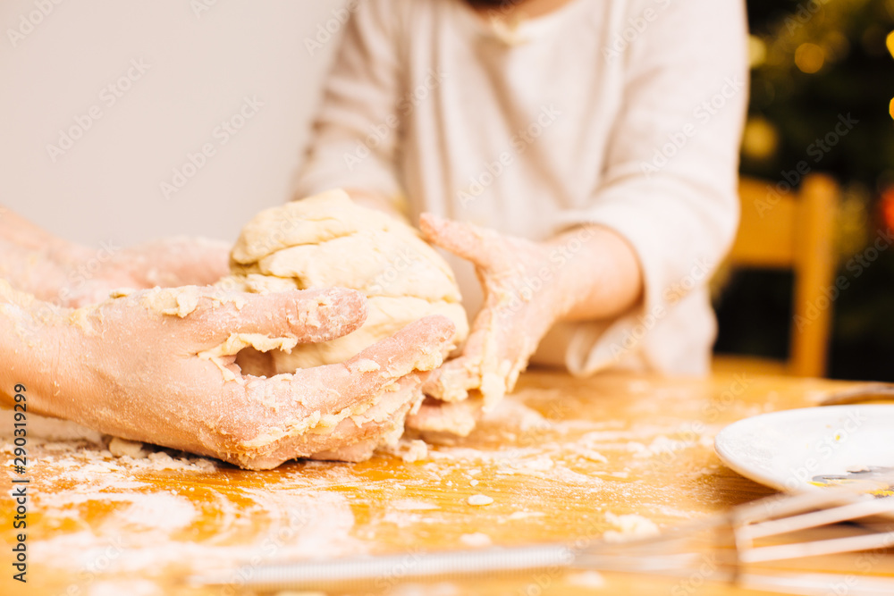 Detail of adult and child hands kneading dough together