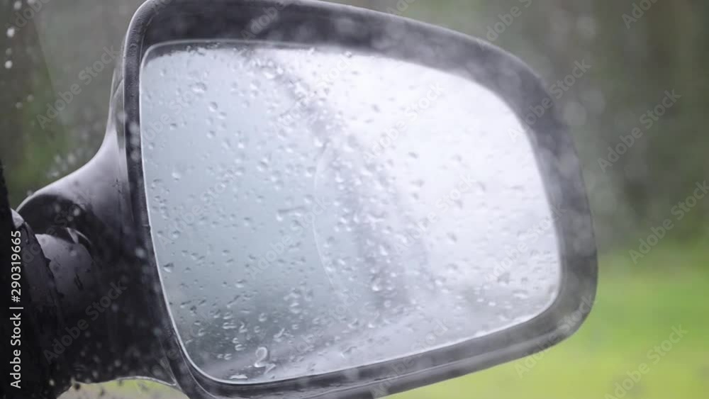 Car side mirror and drivers window with drops of rain sliding down it. Car side mirror and drivers window with drops of rain sliding down it.
