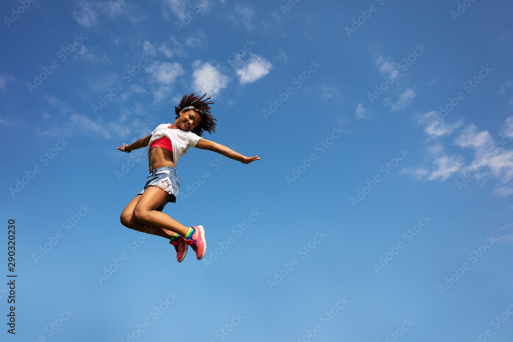 Happy young school age girl jump high over sky Happy young school age girl jump high over sky