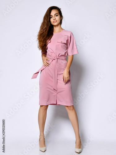 Full length portrait of happy beautiful woman in pink dress posing in studio isolated on white background