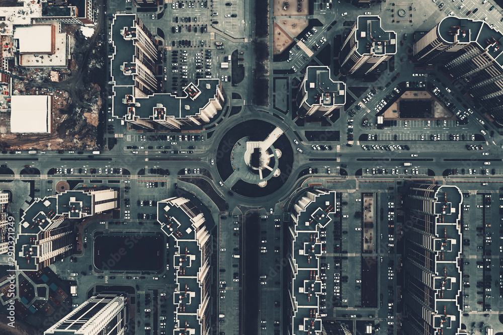 Top down aerial view of round road intersection with cars and new modern buildings, drone shot