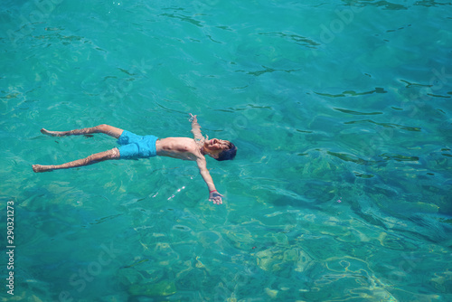 Healthy lifestyle. European boy in blue swim shorts swimming in blue clear sea water during his trip to Spain.
