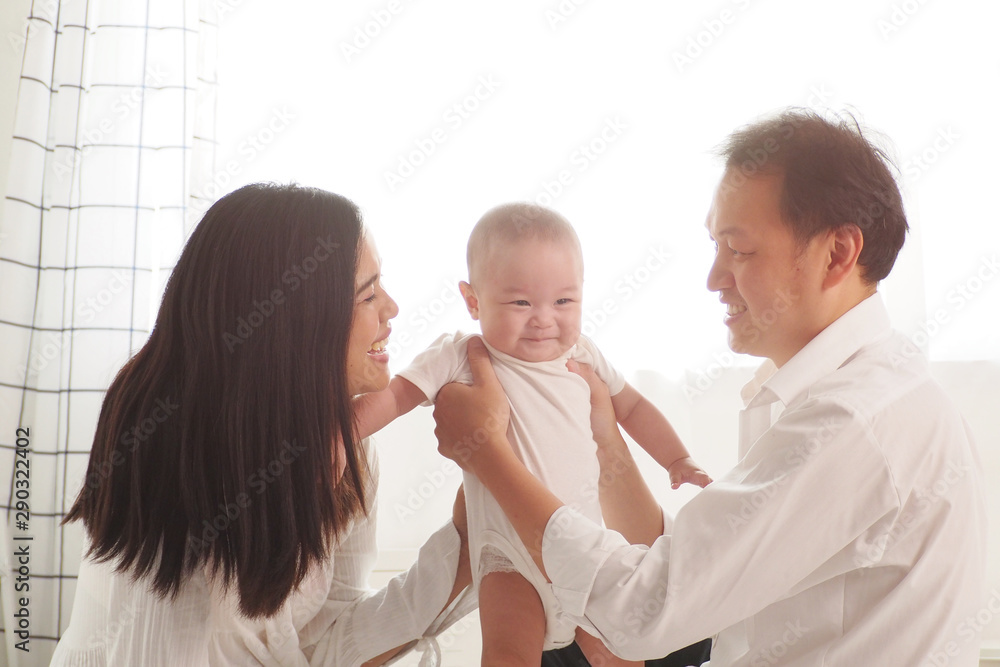 Warm and beautiful moment of Asian parents playing and smiling at their cute newborn baby at home. Good moment for family to spend time together. Happy complete family, love and lifestyle concept Warm and beautiful moment of Asian parents playing and smiling at their cute newborn baby at home. Good moment for family to spend time together. Happy complete family, love and lifestyle concept