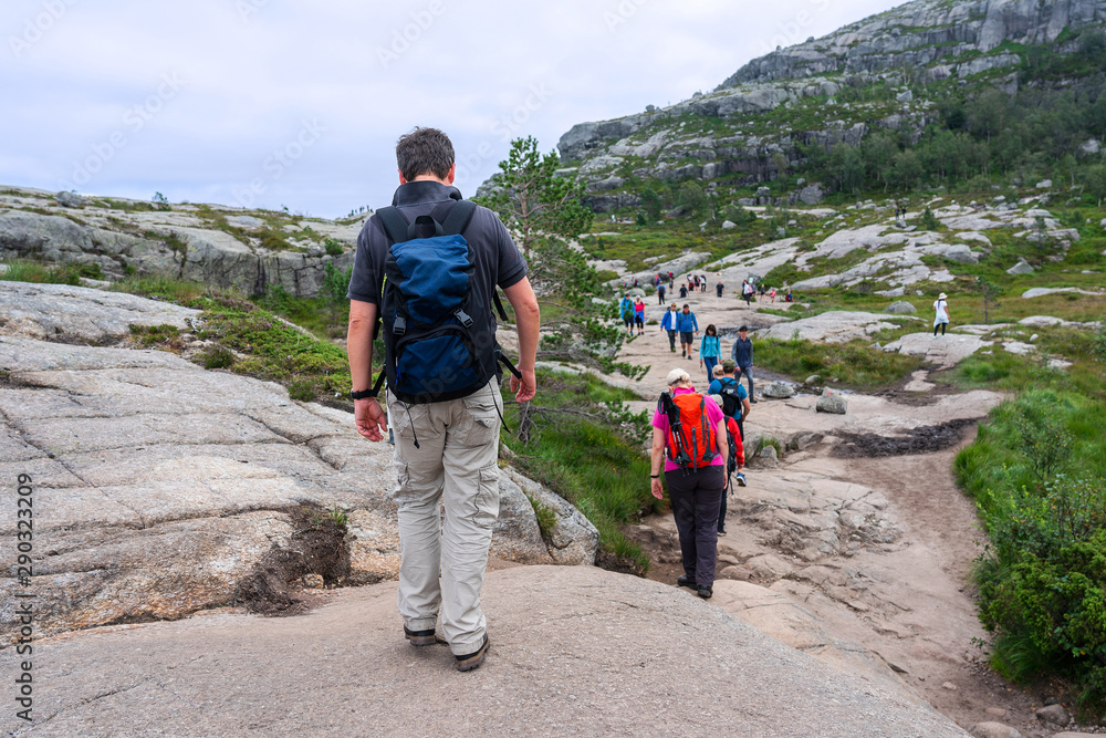 Tourists hiking in mountains, Norway. Way to Preikestolen rock.