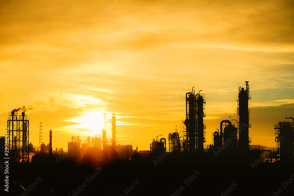 Petrochemical plant or oil and gas refinery industry with distillation tower and smoke stacks in silhouette image on orange sky sunset background