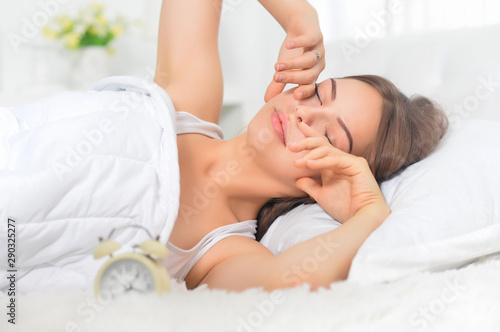 Portrait of young woman awaking on soft bed on morning