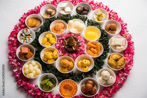 Flower Rangoli with sweets/mithai and diya in bowls for Diwali or any other festivals in India, selective focus