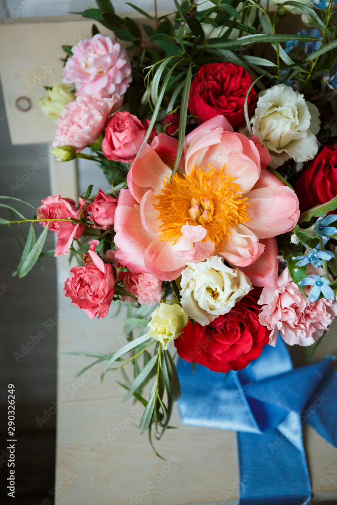 Floristic concept, business concept, gift, surprise, peonies, roses, carnations.  A large multi-colored bouquet stands on a chair. Peony, roses, carnations, eucalyptus, greens, garden flowers