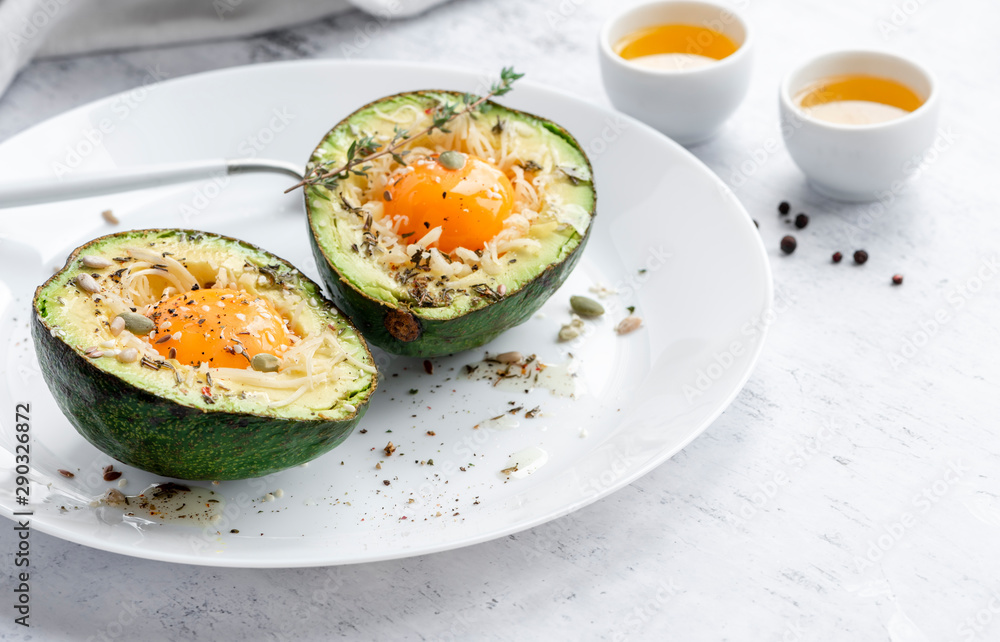 Tasty and healthy avocado snack. Slices of avocado with raw yolk, cheese, olive oil and spices on a white plate close-up.