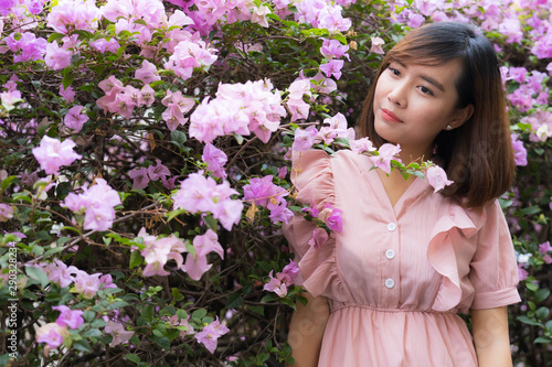 A dreamy girl is imagining in front of bougainvillea.