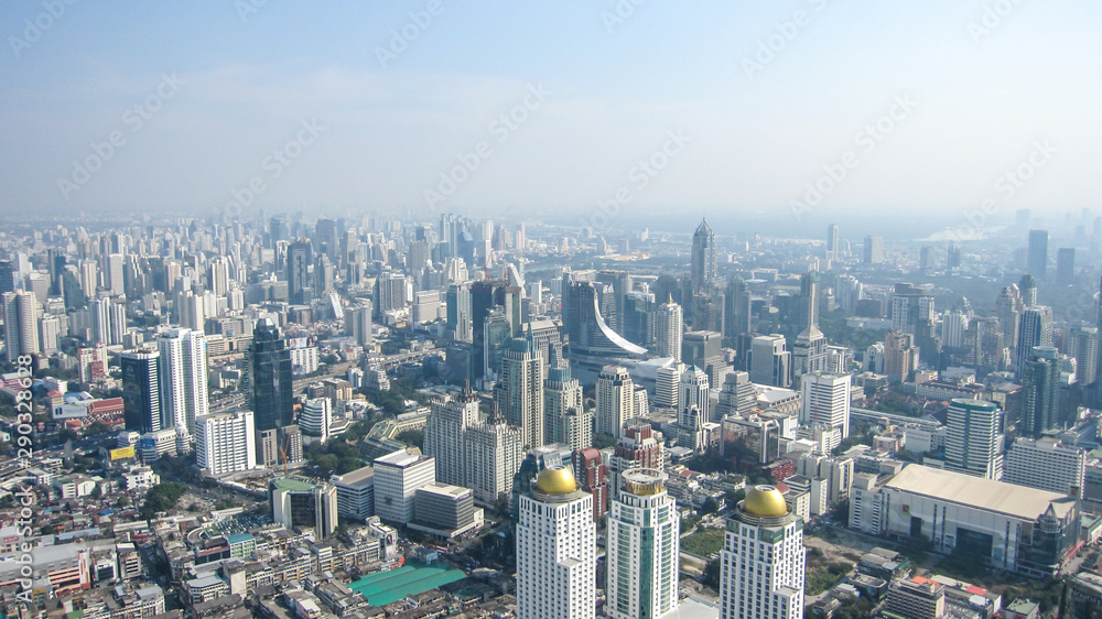 Fototapeta premium high houses of the big city of Bangkok on a clear sunny day, blue sky above them, aerial view
