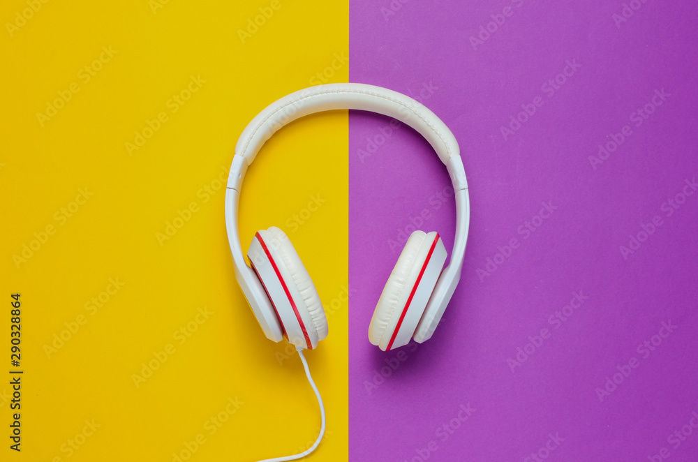 Classic white headphones on purple yellow paper background. Retro style. 80s. Pop culture. Top view. Minimal Music Concept Classic white headphones on purple yellow paper background. Retro style. 80s. Pop culture. Top view. Minimal Music Concept