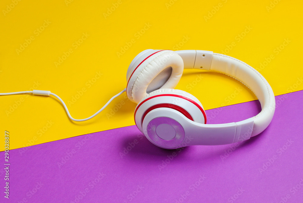 Classic white headphones on purple yellow paper background. Retro style. 80s Pop culture. Classic white headphones on purple yellow paper background. Retro style. 80s Pop culture.