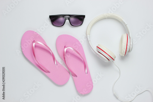 Accessories for relaxing on the beach. Flip flops, headphones, sunglasses. Studio shot on a white background. Top view