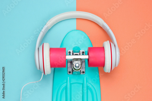 Hipster outfit. Skateboard with headphones on colored background. Creative fashion minimalism. Trendy old fashionable style. Minimal summer fun. Music concept. Top view