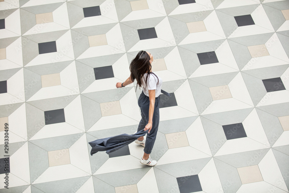 Young adult beautiful brunette girl happy on tile with geometric pattern top view Young adult beautiful brunette girl happy on tile with geometric pattern top view