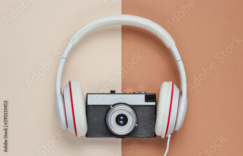 Headphones with a retro camera on a brown-beige background. Top view, minimalism