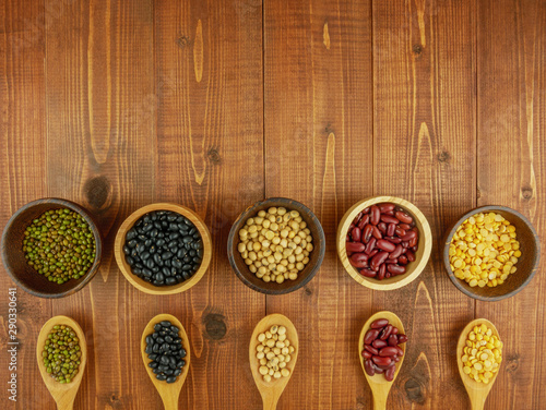 Flat lay,top view assorted beans including red bean,soybeans,black beans,mung beans on brown,beige wooden background with copy space