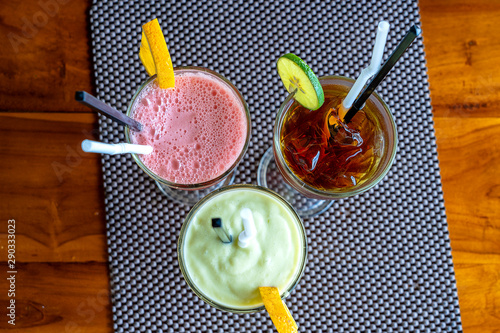 Avocado smoothie, watermelon shake and cold tea in a glass on a wooden table. Tropical drink concept . Top view, closeup