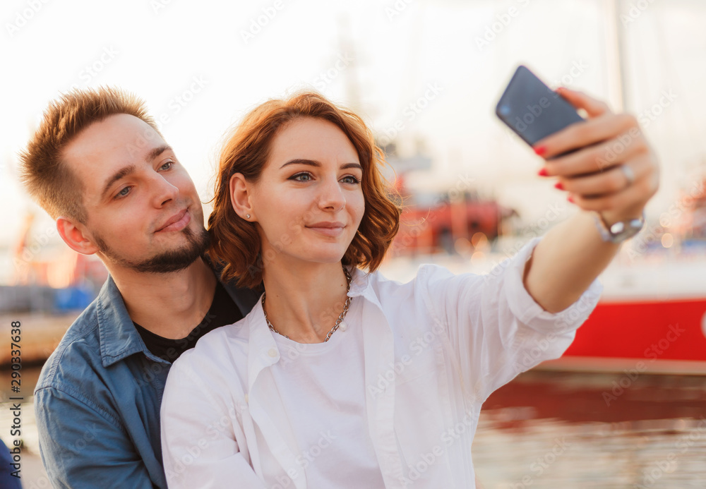 Young smiling couple in love makes selfie portrait with phone. Romantic concept