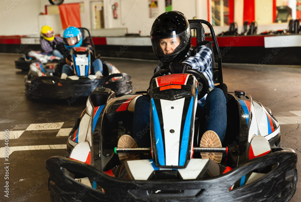 Female racer in helmet driving kart on track