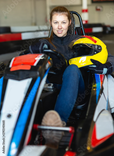 Female racer holding helmet on kart track