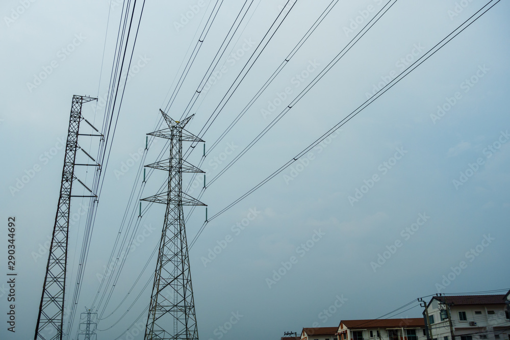 Transmission tower close to village in rainy day, Transmission tower with cloudy sky background.